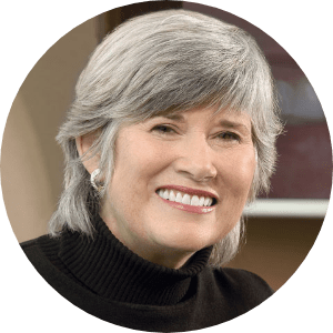 Smiling woman with gray hair wearing a black turtleneck.